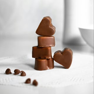 Photo by Sara Cervera on Unsplash: Heart Shaped Chocolates on a white background with kisses in the foreground